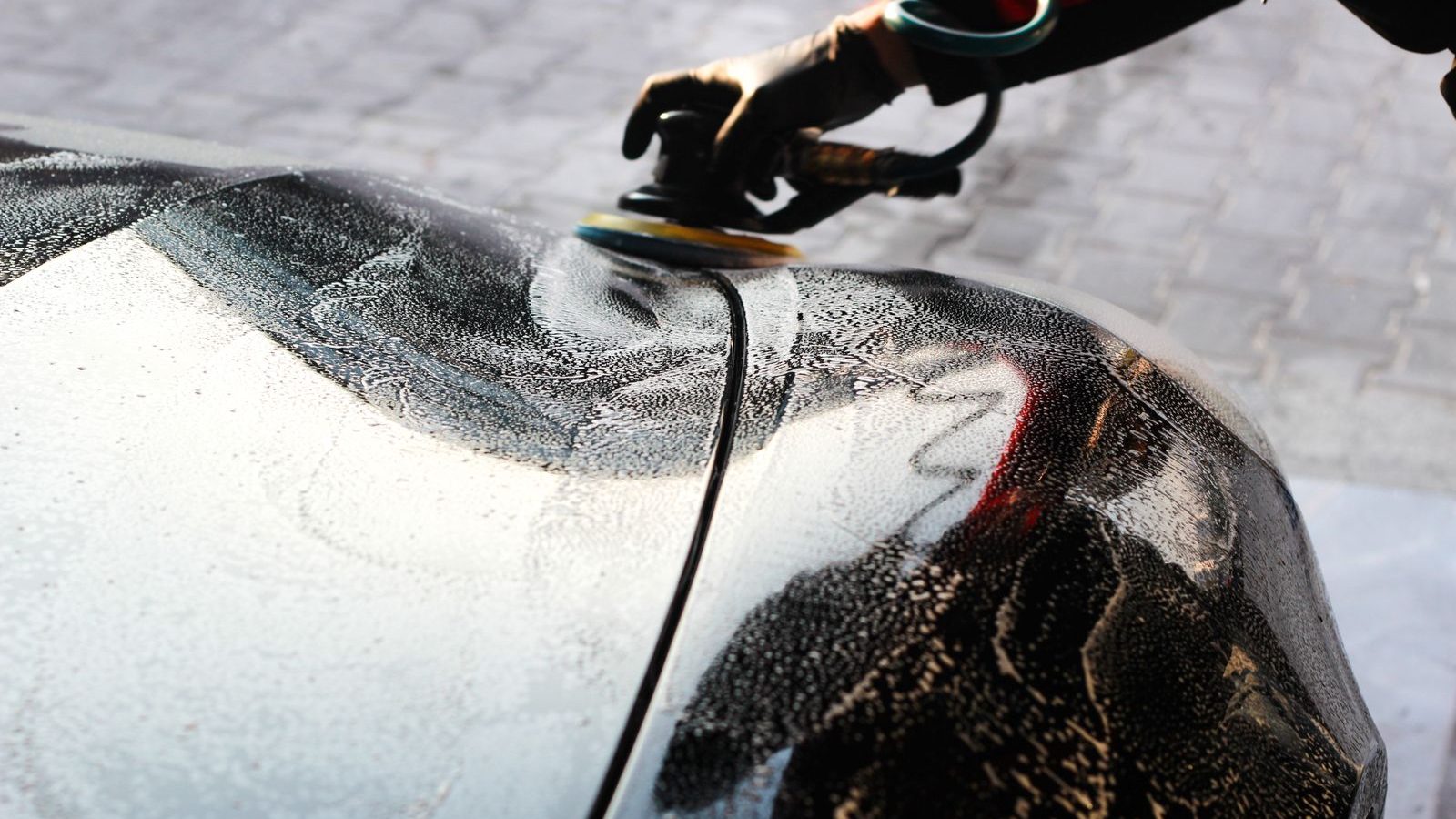Detailer poliert eine Fahrzeughaube mit der Poliermaschine