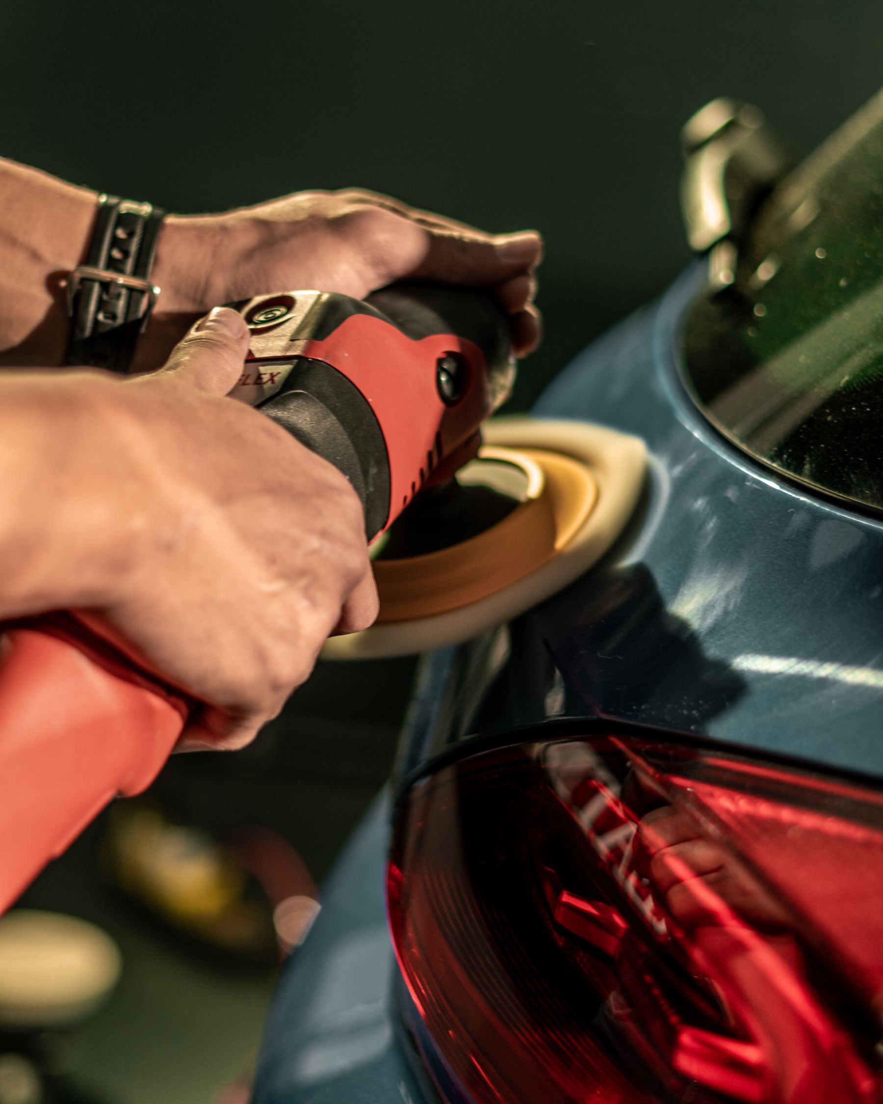 Detailer poliert die Heckpartie eines Autos mit einer Poliermaschine